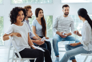 Woman looks out from a group therapy meeting for addiction.
