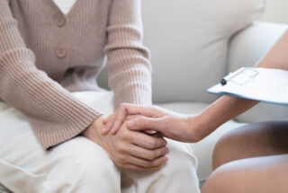 Woman holding hand of another woman in CBT for addiction.