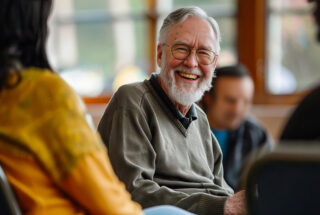 Many smiling during a session of group CBT for addiction.