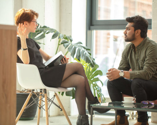 Woman and man in a counseling session, engaged in conversation in a bright office