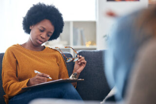 addiction counselor taking notes durign therapy session to treat some with opiate addiction