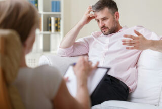 Confused man talking with doctor about prescription drug addiction.