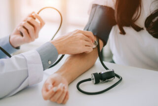 Doctor taking blood pressure reading of woman in stimulant addiction treatment.