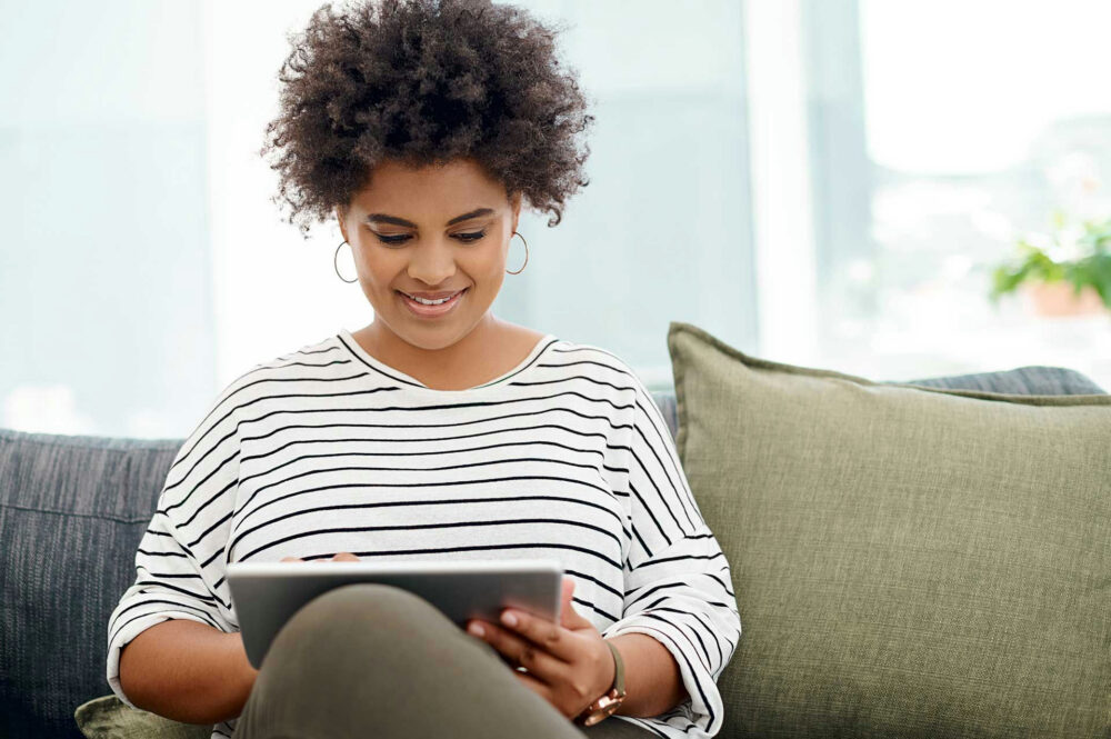 Woman smiling while using her tablet at home in recovery