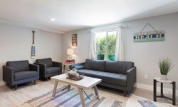 Cozy living area with gray chairs, a beach-themed wall sign